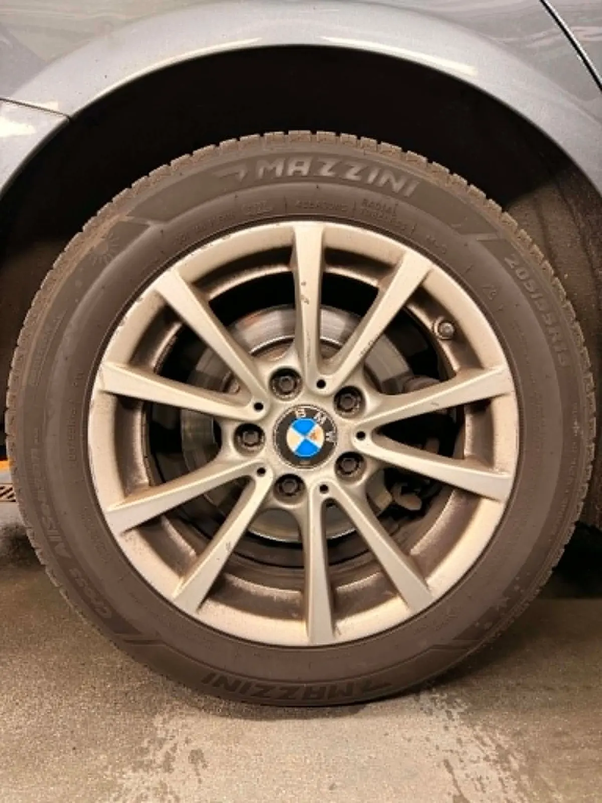 Aluminiowa felga BMW pokryta warstwą pyłu hamulcowego, matowa opona i zabrudzone wnętrze koła