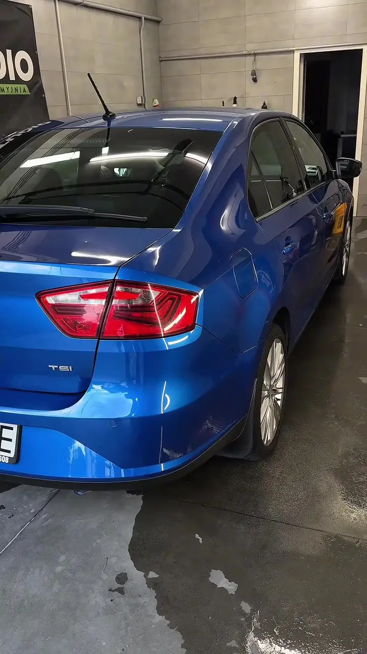 Niebieski sedan z czystym, błyszczącym lakierem w studiu detailingowym