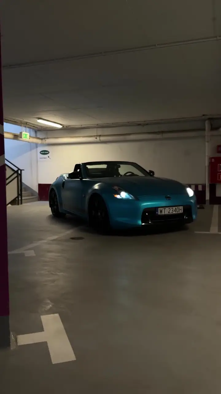 Sportowy roadster oklejony turkusową folią wyjeżdżający z parkingu podziemnego